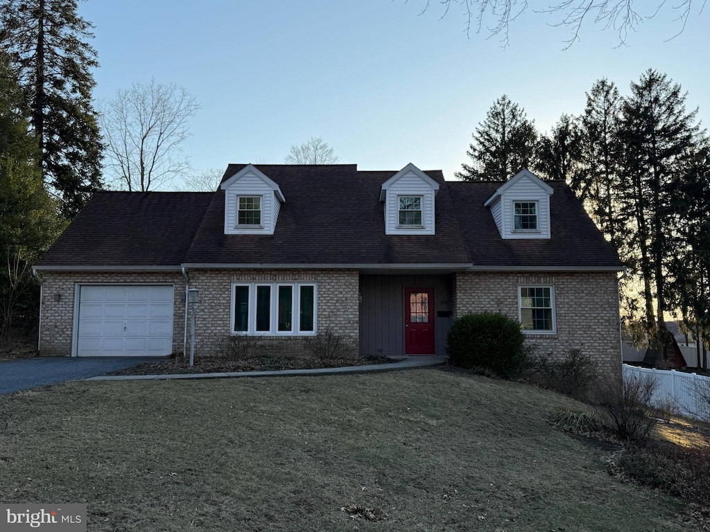 cape cod house with a front lawn, brick siding, a garage, and driveway