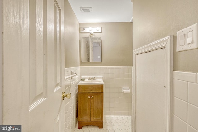 bathroom featuring tile patterned floors, visible vents, tile walls, wainscoting, and vanity