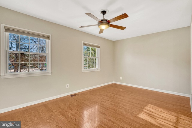 unfurnished room with ceiling fan, visible vents, baseboards, and wood finished floors