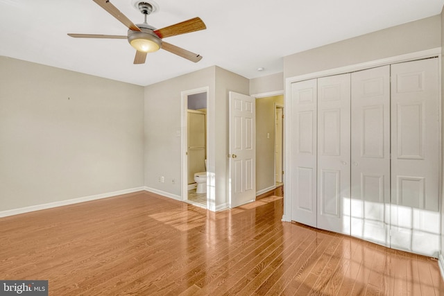 unfurnished bedroom featuring wood finished floors, baseboards, ceiling fan, a closet, and connected bathroom