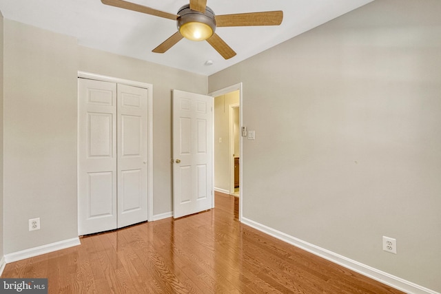 unfurnished bedroom with light wood-style flooring, a ceiling fan, baseboards, and a closet