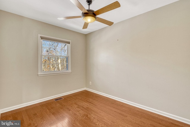 empty room featuring visible vents, a ceiling fan, baseboards, and wood finished floors