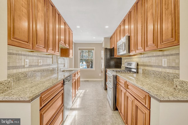 kitchen featuring a sink, appliances with stainless steel finishes, crown molding, baseboards, and light stone countertops