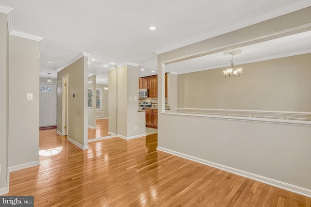 spare room with light wood-type flooring, baseboards, a chandelier, and ornamental molding