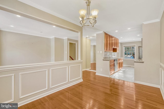 unfurnished dining area featuring a sink, light wood-type flooring, a chandelier, and crown molding