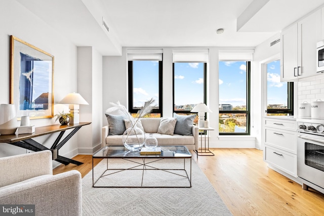 living area with baseboards, visible vents, and light wood finished floors