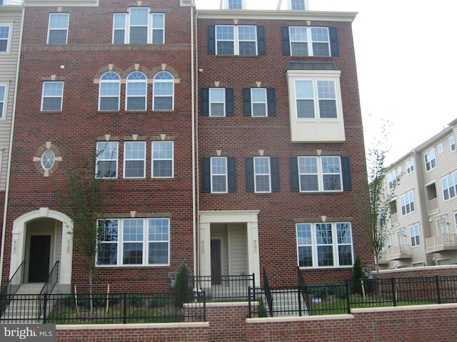 multi unit property with brick siding and a fenced front yard