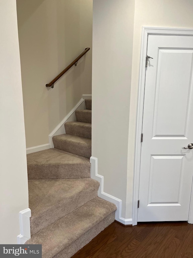 staircase featuring baseboards and wood finished floors