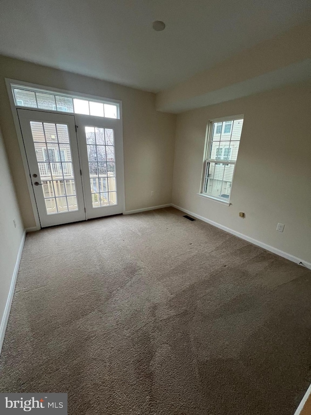 carpeted spare room featuring visible vents and baseboards