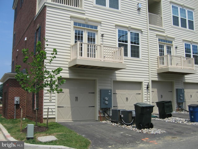 view of front of home with central AC, brick siding, a garage, and driveway