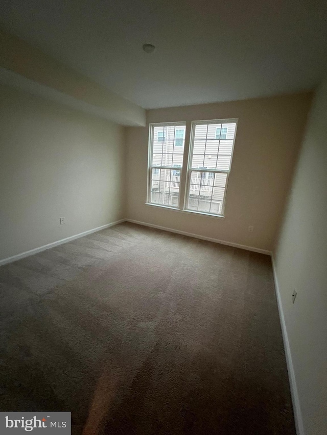 spare room featuring carpet flooring and baseboards