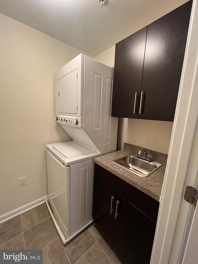 washroom with baseboards, cabinet space, a sink, indoor wet bar, and stacked washer and clothes dryer