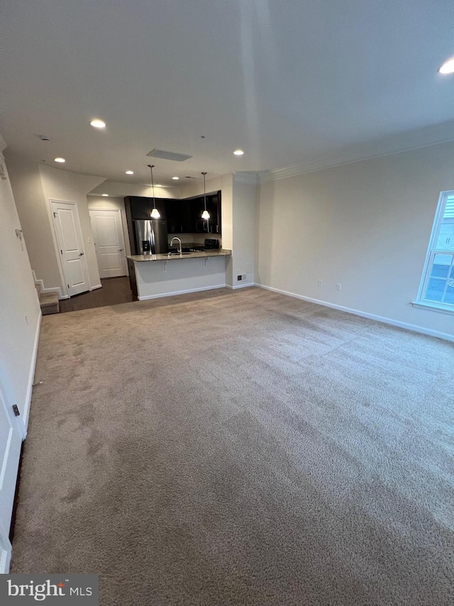 unfurnished living room with recessed lighting, dark carpet, baseboards, and a sink