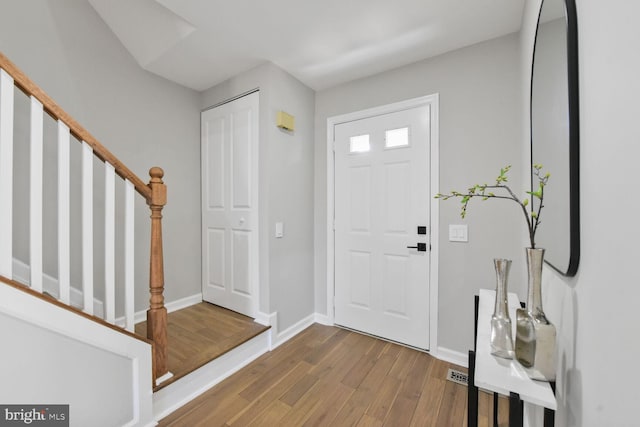 entryway with stairway, wood finished floors, and baseboards