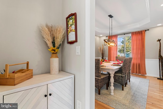 dining room with a tray ceiling, recessed lighting, wood finished floors, and ornamental molding