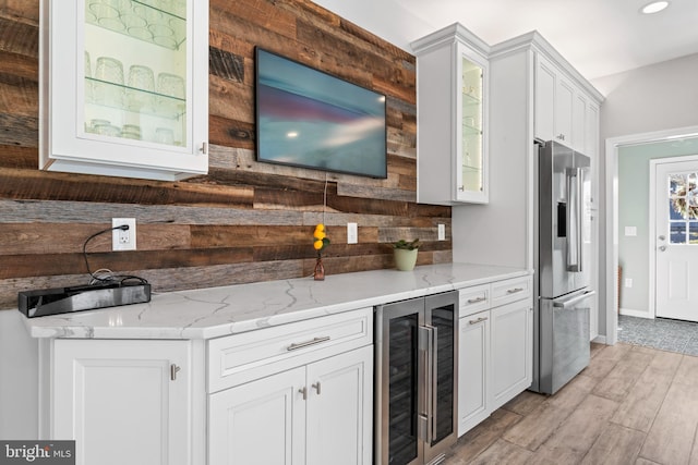 kitchen with light stone countertops, beverage cooler, white cabinets, glass insert cabinets, and high quality fridge