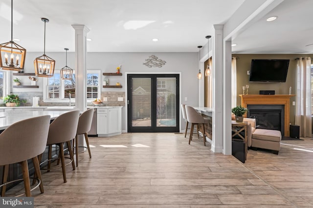 interior space featuring backsplash, white cabinets, light wood-type flooring, and open shelves