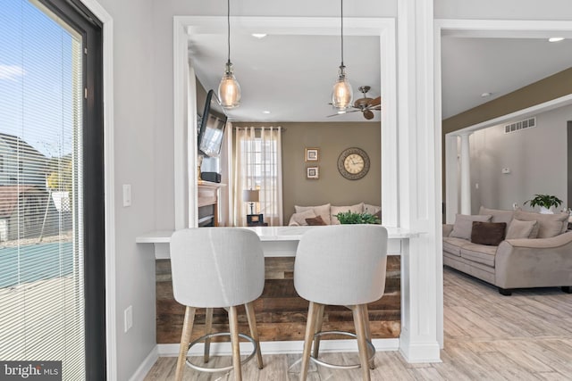 dining area featuring visible vents, baseboards, wood finished floors, and decorative columns