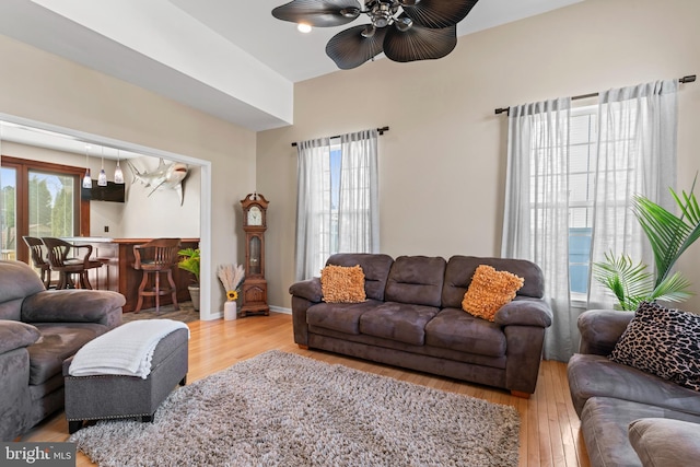 living area featuring hardwood / wood-style floors, baseboards, and ceiling fan