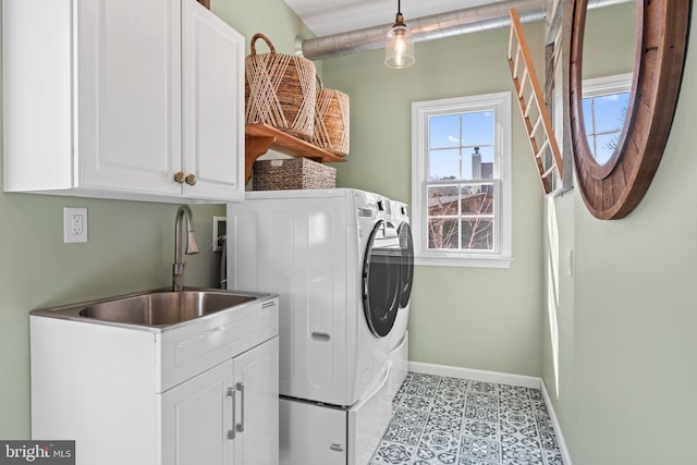 laundry room featuring tile patterned floors, a sink, washing machine and dryer, cabinet space, and baseboards