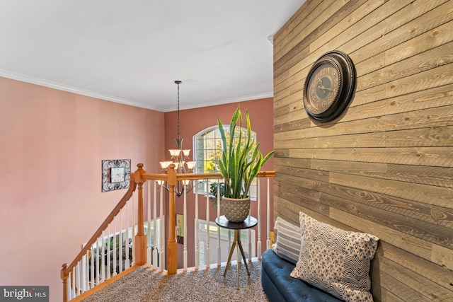 corridor featuring an upstairs landing, carpet floors, an inviting chandelier, and crown molding