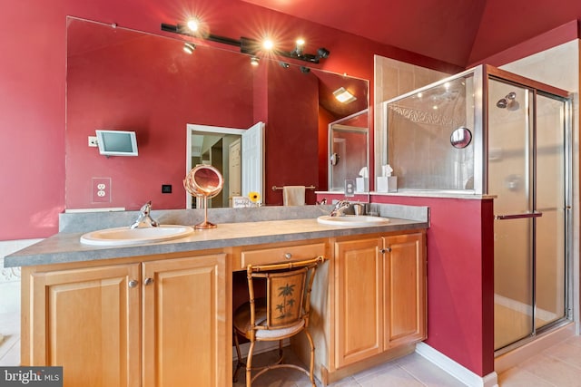 full bathroom featuring tile patterned flooring, double vanity, a stall shower, and a sink