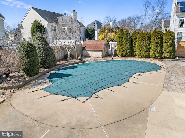 view of swimming pool with a storage unit, fence, an outdoor structure, a fenced in pool, and a patio area