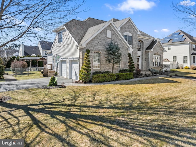 view of front of house with fence, driveway, an attached garage, a front lawn, and brick siding