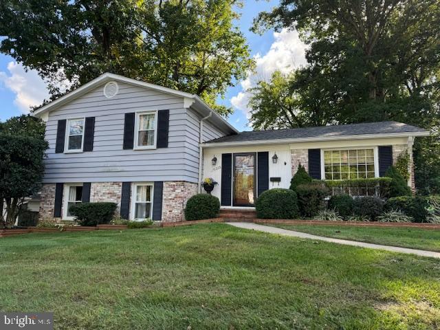 tri-level home featuring a front yard and brick siding