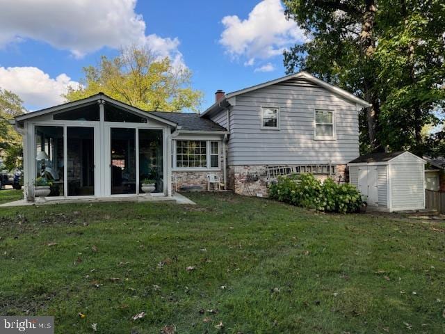 back of house with a yard, a shed, an outdoor structure, and a sunroom