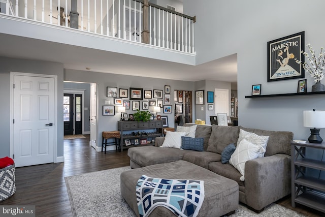 living room featuring a high ceiling, baseboards, and wood finished floors