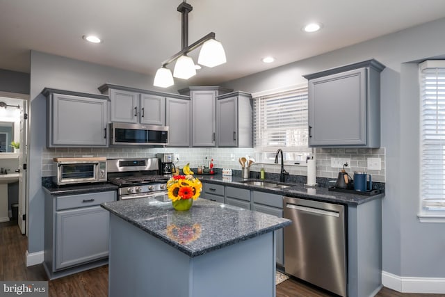 kitchen with gray cabinetry, a sink, backsplash, appliances with stainless steel finishes, and a toaster