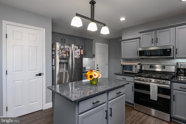 kitchen with a kitchen island, decorative backsplash, gray cabinets, appliances with stainless steel finishes, and dark wood-style flooring