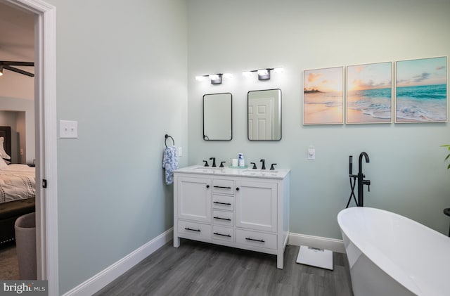 full bathroom with a freestanding tub, connected bathroom, baseboards, and wood finished floors