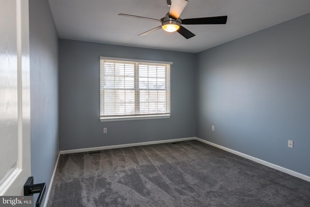 empty room featuring dark colored carpet, baseboards, and ceiling fan