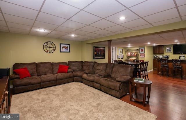 living area with dark wood finished floors, a drop ceiling, recessed lighting, and bar area