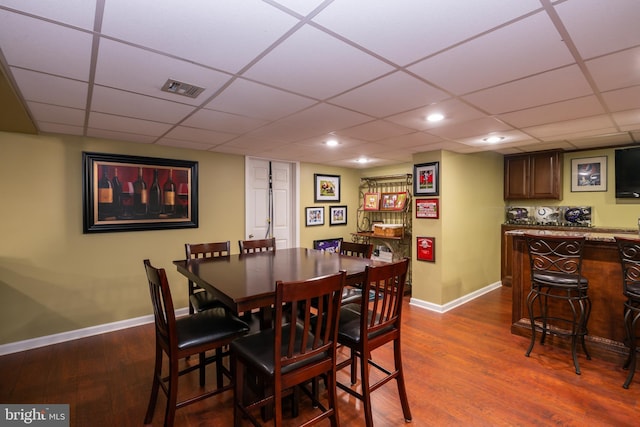 dining space with visible vents, baseboards, dark wood finished floors, recessed lighting, and a dry bar