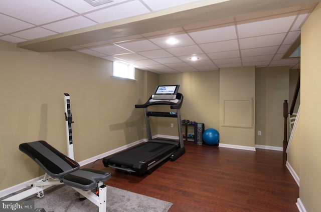 workout area with recessed lighting, wood finished floors, baseboards, and a paneled ceiling