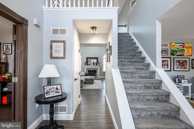 stairway featuring visible vents, a fireplace, baseboards, and wood finished floors