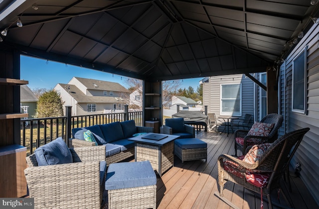 wooden deck featuring outdoor dining area, an outdoor living space with a fire pit, a gazebo, grilling area, and a residential view