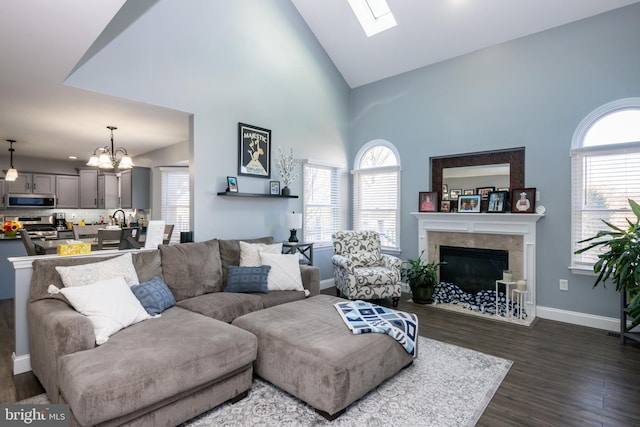 living area featuring a healthy amount of sunlight, a fireplace, dark wood-type flooring, and baseboards