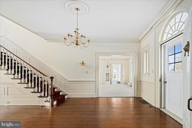 foyer entrance with a decorative wall, wood finished floors, a wealth of natural light, and ornamental molding