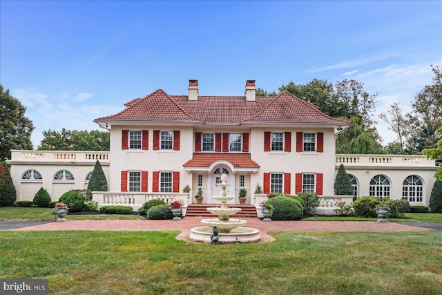 view of front of house with a chimney, a front lawn, and a tiled roof