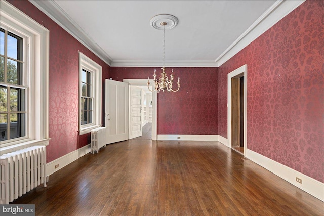 unfurnished dining area featuring a notable chandelier, radiator, wallpapered walls, and wood finished floors