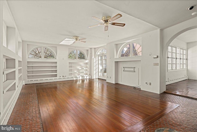 unfurnished living room featuring hardwood / wood-style floors, built in shelves, a ceiling fan, and a baseboard radiator