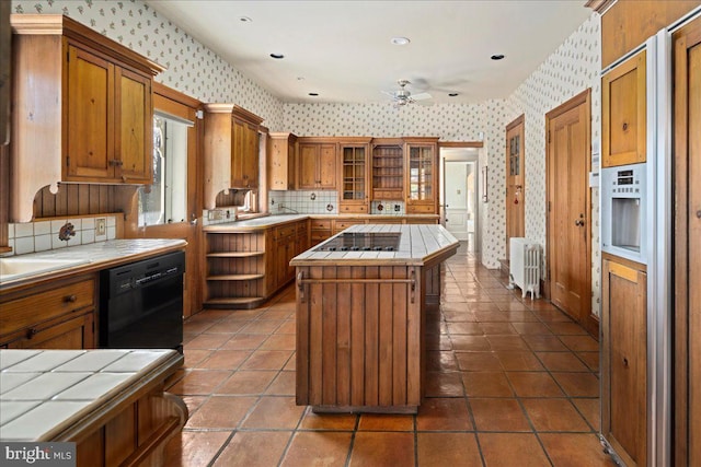 kitchen with a center island, wallpapered walls, tile counters, dishwasher, and radiator heating unit