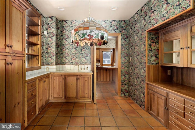 kitchen featuring open shelves, a sink, tile countertops, wallpapered walls, and light tile patterned floors