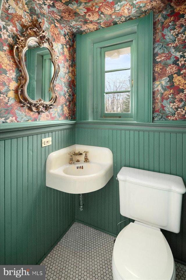 bathroom featuring wallpapered walls, toilet, and wainscoting