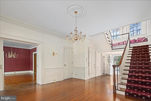 interior space featuring wood finished floors, an inviting chandelier, stairs, wainscoting, and crown molding