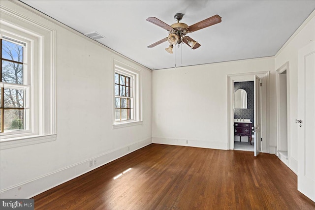 unfurnished room with visible vents, a healthy amount of sunlight, wood finished floors, and a ceiling fan